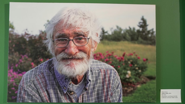 Une photo d'un homme assez âgé, à la chevelure et à la barbe blanches. Il porte des lunettes. 