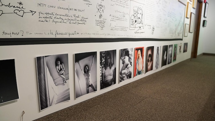 Une série de photos sous un grand tableau sur lequel sont inscrits des dizaines de messages, à l'encre noire. 