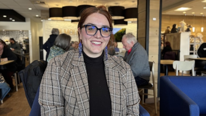 Marianne Thibeault sourit à la caméra, vêtue d'un tailleur. Elle est assise dans un chic café.
